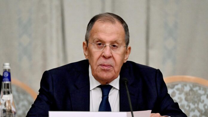 Russian Foreign Minister Sergey Lavrov seated at a table with a microphone and papers in front of him