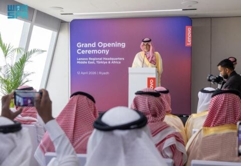A speaker at a podium during the grand opening ceremony of Lenovo's regional headquarters in Riyadh, with an audience in Saudi headdress in the foreground