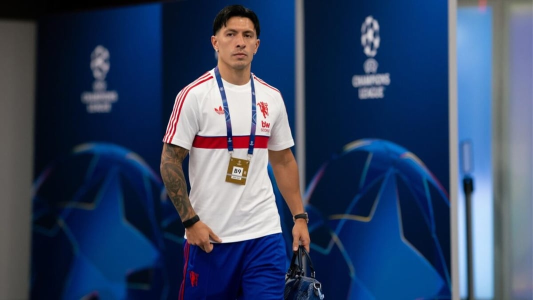 Lisandro Martinez in a Manchester United training top walking through a corridor lined with Champions League branding
