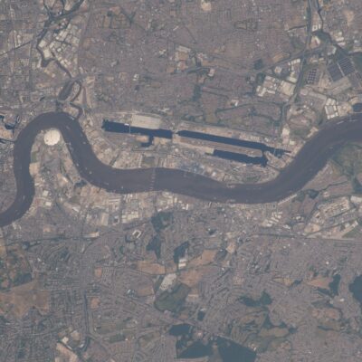 An aerial view from orbit of the River Thames winding through east London past Canary Wharf and London City Airport