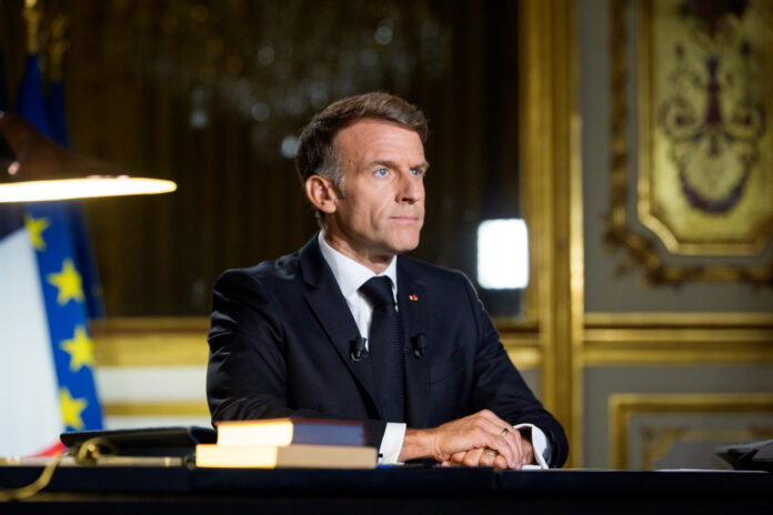 Emmanuel Macron seated at a desk in the Elysee Palace in a photograph published with the text of his Sunday address