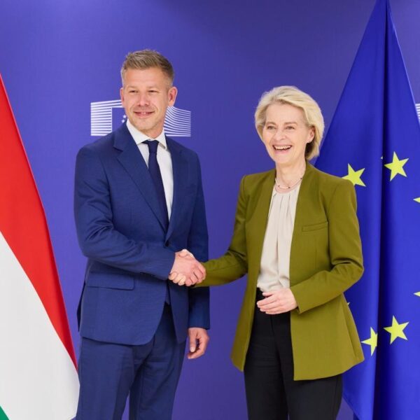 Hungarian Prime Minister Peter Magyar and European Commission President Ursula von der Leyen shake hands in front of Hungarian and EU flags