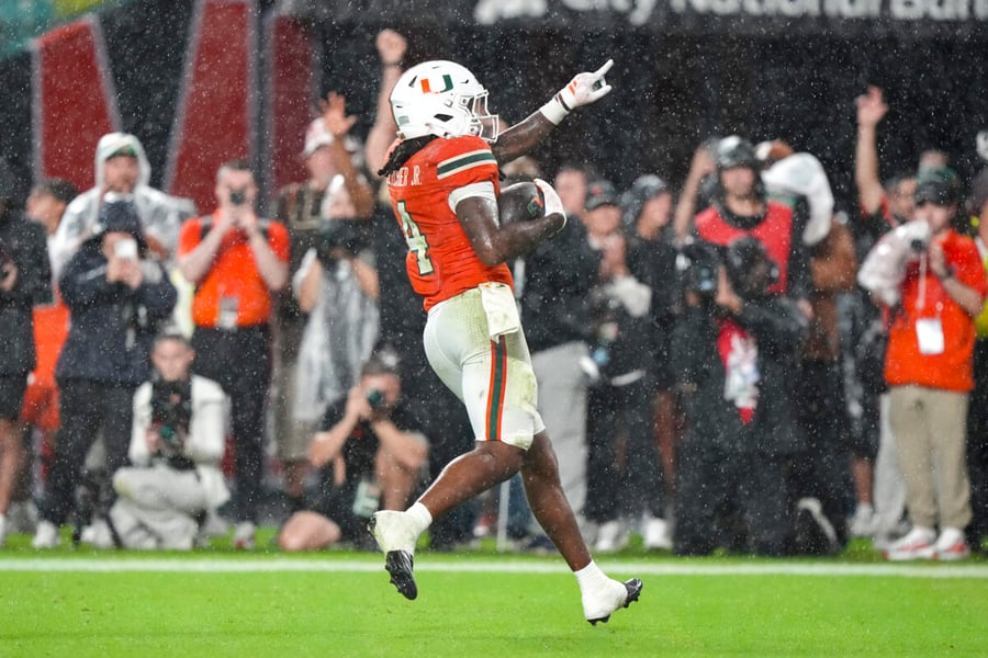 Miami's Mark Fletcher Jr. holds the ball and points upward while celebrating in the rain during the Hurricanes' win over Florida State.