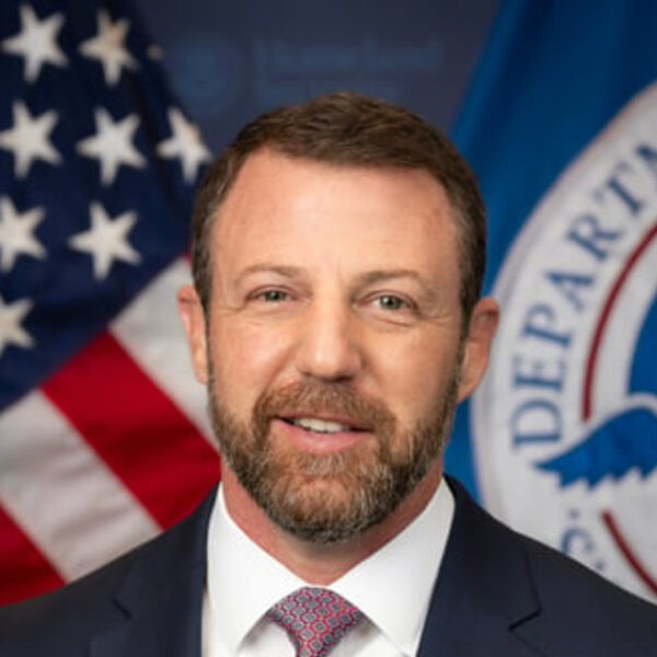 Homeland Security Secretary Markwayne Mullin in an official portrait with the US and Department of Homeland Security flags behind him