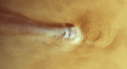 White water ice cloud streaming from the Arsia Mons volcano across the tan surface of Mars, seen from above by Mars Express