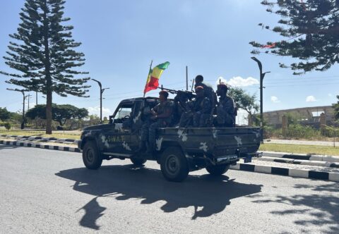 Armed Ethiopian security personnel ride on the back of a pickup truck flying an Ethiopian flag on a road in Mekelle
