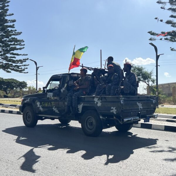Armed Ethiopian security personnel ride on the back of a pickup truck flying an Ethiopian flag on a road in Mekelle