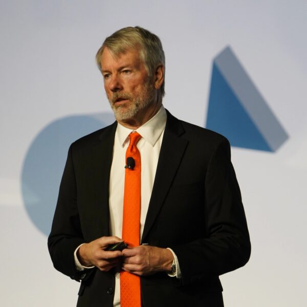 Strategy Executive Chairman Michael Saylor in a dark suit and orange tie speaking on stage