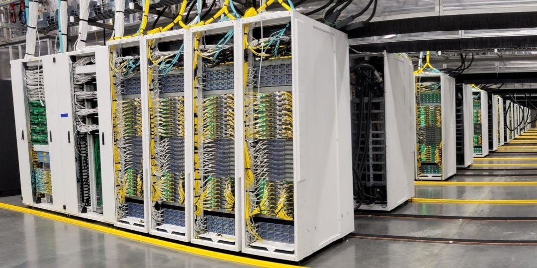 Rows of white server racks with yellow and blue cabling in a Microsoft AI datacenter