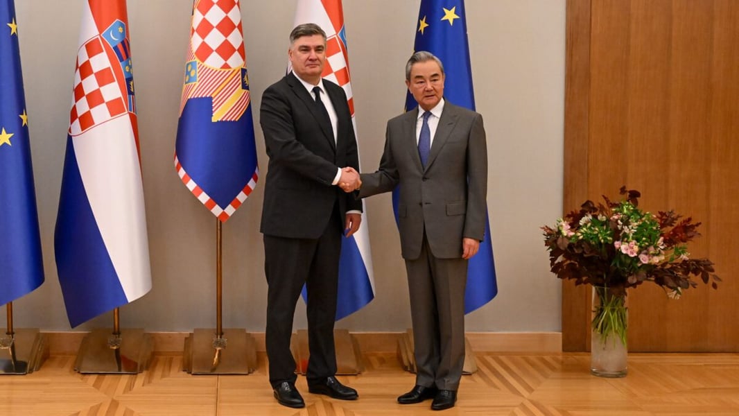Croatian President Zoran Milanovic shakes hands with Chinese Foreign Minister Wang Yi in front of Croatian and EU flags in Zagreb