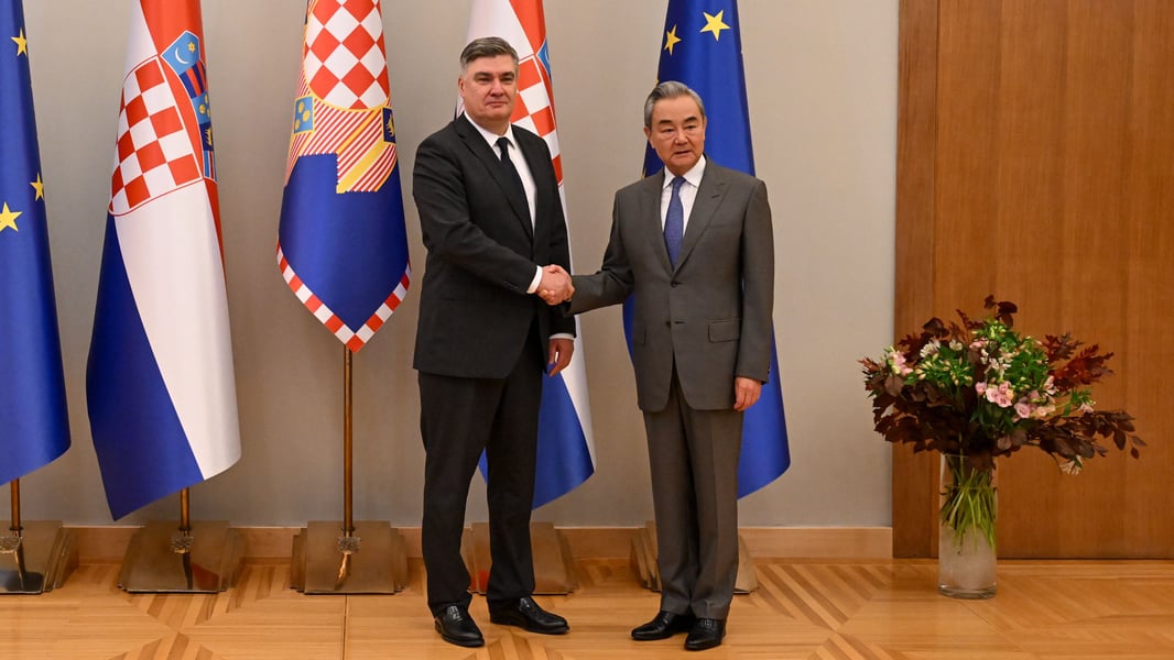 Croatian President Zoran Milanovic shakes hands with Chinese Foreign Minister Wang Yi in front of Croatian and EU flags in Zagreb