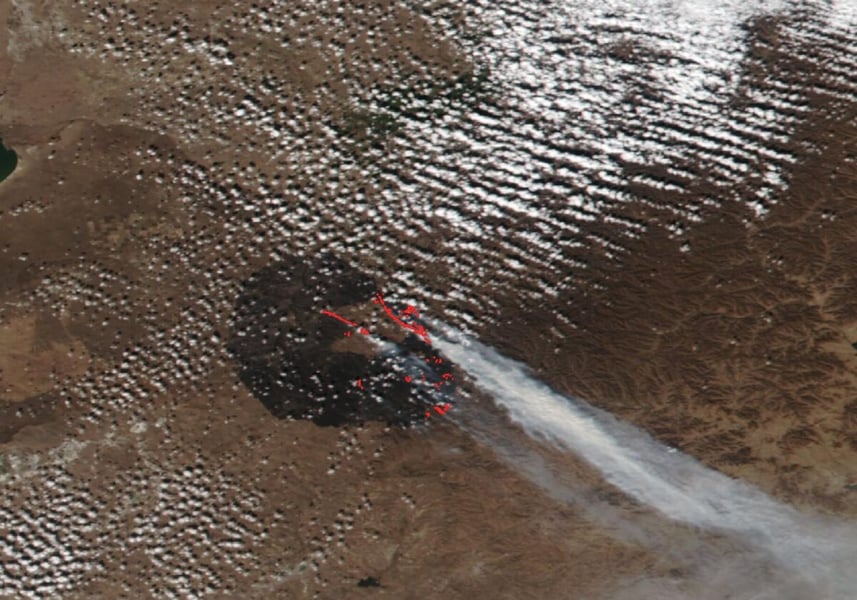 Satellite image of eastern Mongolia with a dark burn scar, red heat detections and a long smoke plume streaming south-east