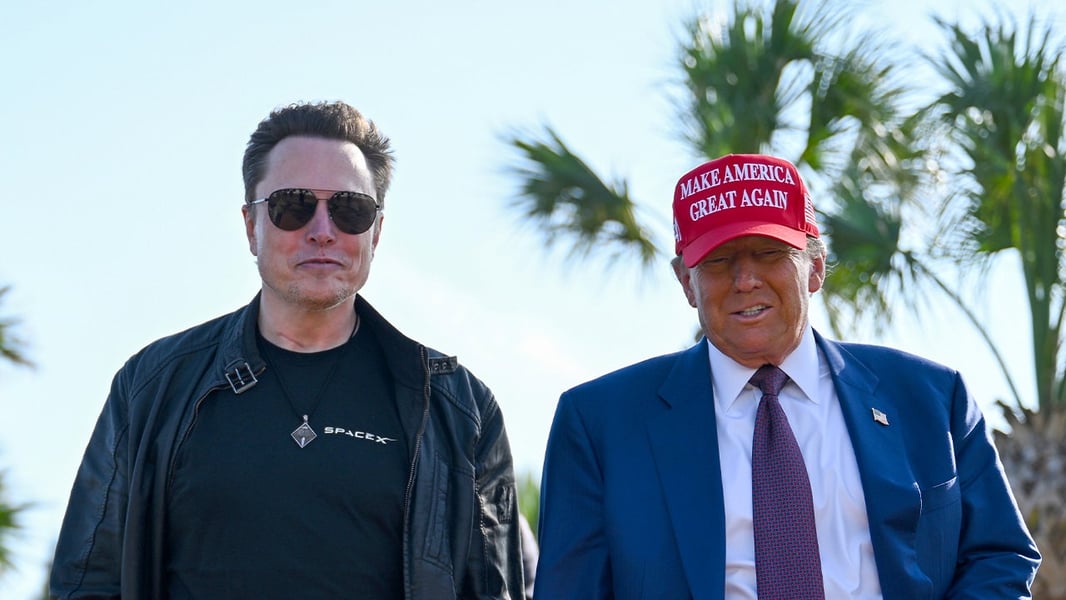 Elon Musk in a SpaceX shirt and sunglasses stands beside President Donald Trump in a red Make America Great Again cap