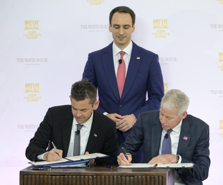 NASA Administrator Jared Isaacman and Energy Secretary Chris Wright sign a memorandum at a table as OSTP Director Michael Kratsios stands behind them