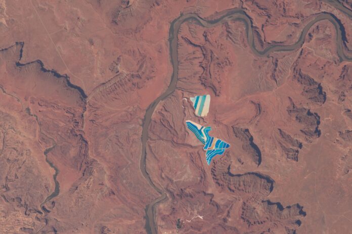 Blue and white potash evaporation ponds beside a river bend in the red rock desert near Moab, Utah, seen from the International Space Station