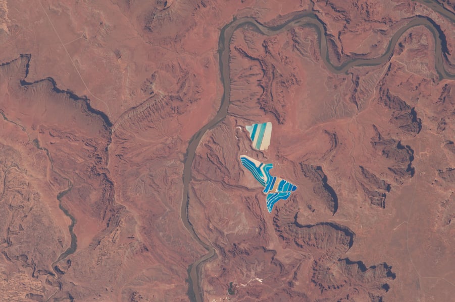 Blue and white potash evaporation ponds beside a river bend in the red rock desert near Moab, Utah, seen from the International Space Station