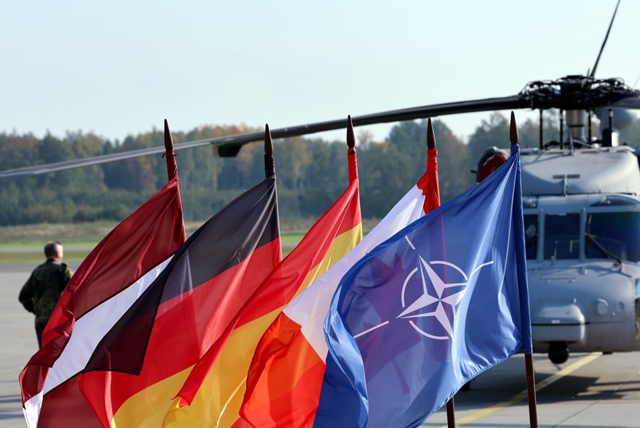 Latvian, German, Spanish, Canadian and NATO flags in front of a helicopter at Lielvarde Air Base in Latvia