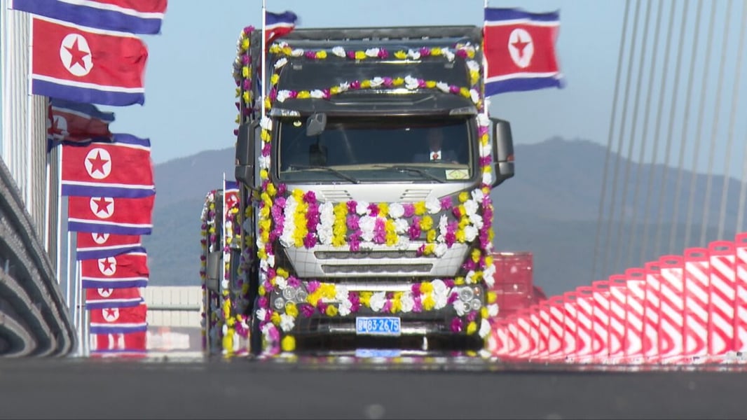 A flower-decorated truck passes rows of North Korean flags on the New Yalu River Bridge on opening day
