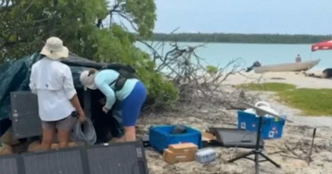 Researchers handle equipment at a camp on the shore of Nikumaroro's lagoon during the October 2026 Earhart expedition
