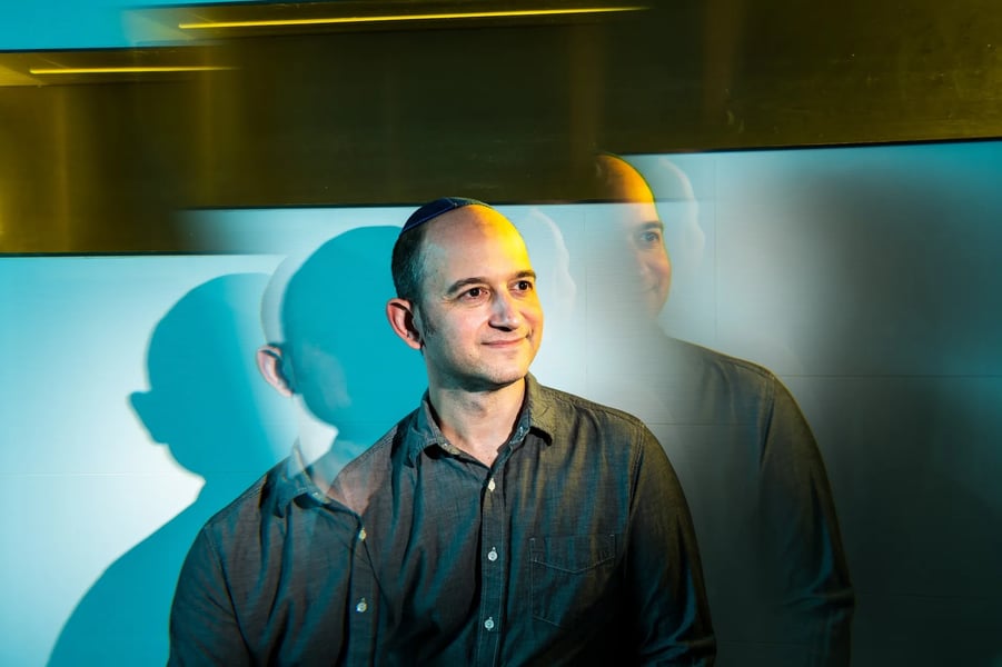 Noam Shazeer, co-founder of Character.AI, photographed against a blue-lit wall