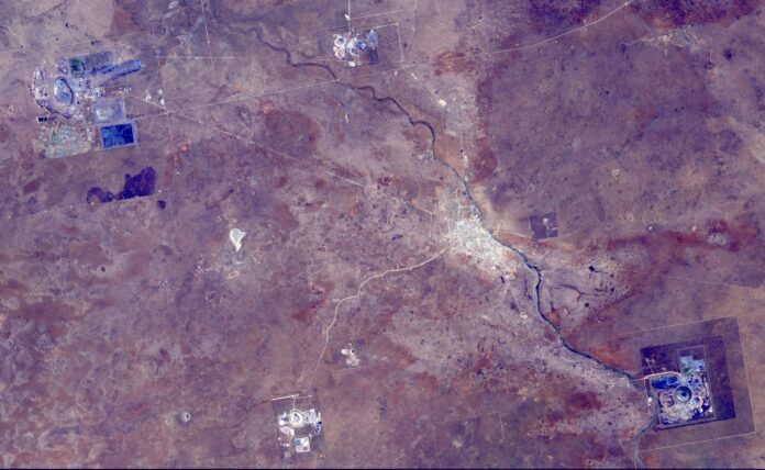 Satellite image of the Orapa diamond mine area in Botswana, with open-pit mines and tailings pale against a purple-brown landscape