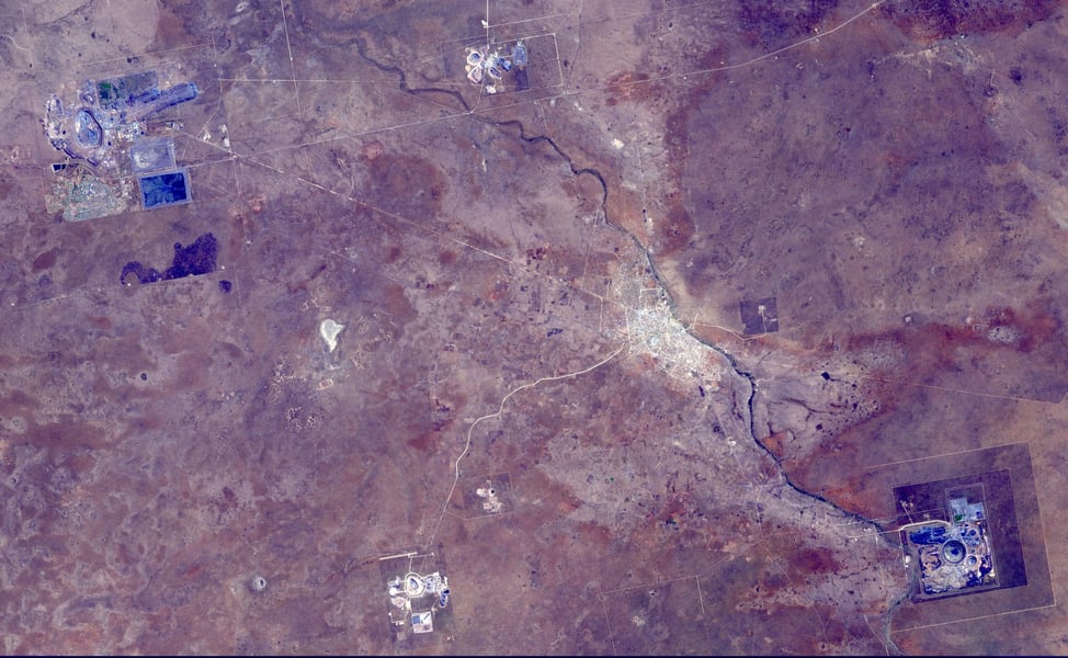 Satellite image of the Orapa diamond mine area in Botswana, with open-pit mines and tailings pale against a purple-brown landscape