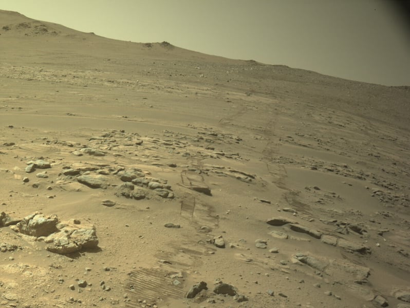 Rover tracks crossing a rocky slope on the western rim of Jezero Crater, seen by Perseverance's navigation camera
