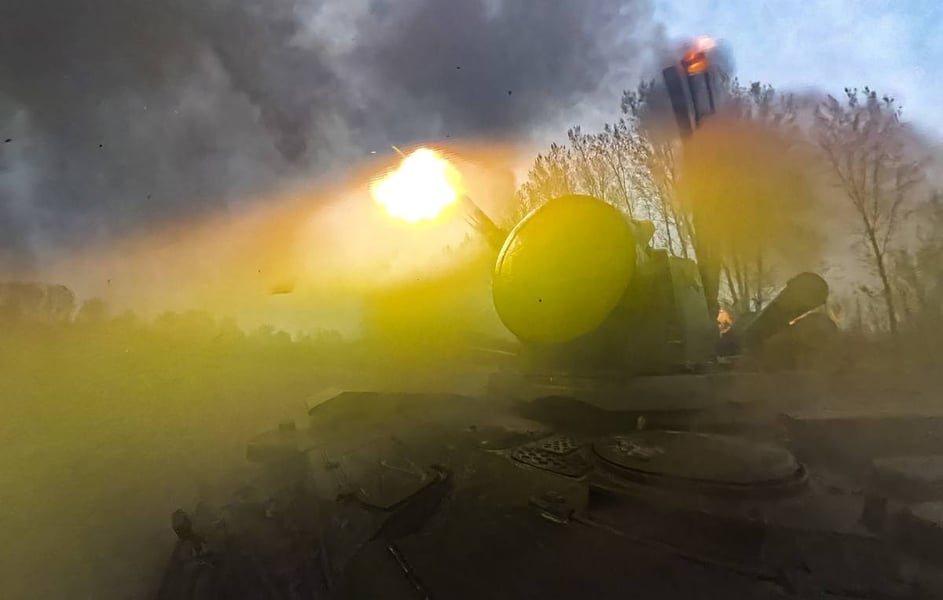 An air defense vehicle fires, with a muzzle flash and smoke around its turret