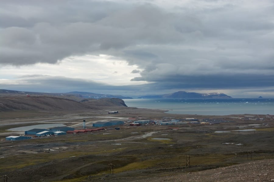 The buildings, runway and control tower of Pituffik Space Base on a coastal plain in Greenland under heavy cloud