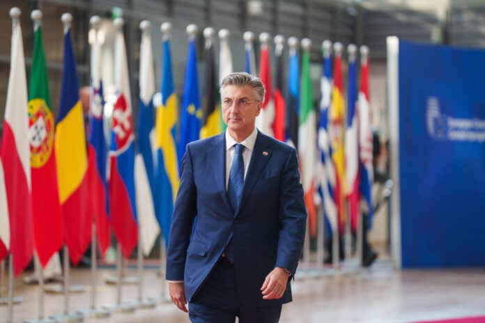 Croatian Prime Minister Andrej Plenkovic walks past a row of national flags at the European Council in Brussels