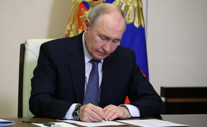 Vladimir Putin takes notes at a desk during the meeting on improving information security at Novo-Ogaryovo