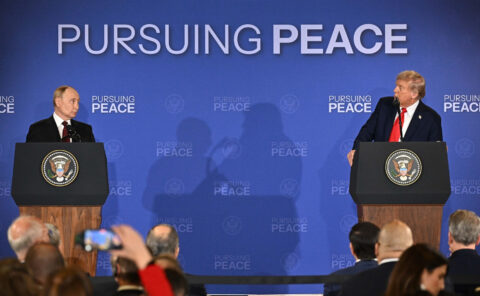 Vladimir Putin and Donald Trump at separate lecterns during their joint news conference in Anchorage, Alaska, under a Pursuing Peace backdrop