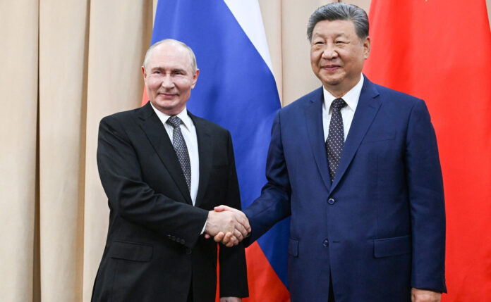 Vladimir Putin and Xi Jinping shaking hands in front of Russian and Chinese flags