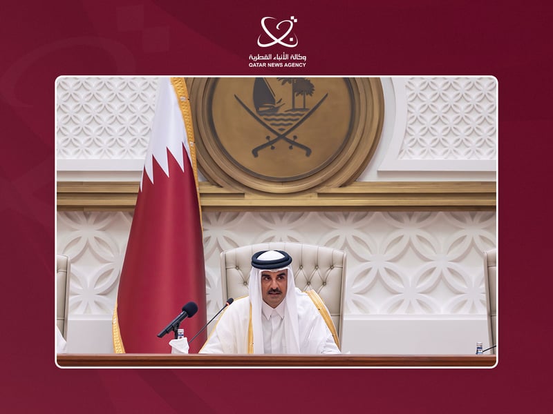 Qatar's Emir Sheikh Tamim bin Hamad Al Thani seated at a microphone before the national flag as he addresses the Shura Council