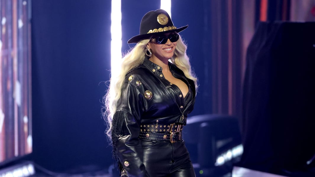 Beyoncé in a black leather outfit and hat smiling onstage at the 2024 iHeartRadio Music Awards