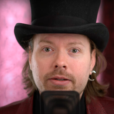 Richard Heart, founder of HEX, PulseChain and PulseX, wearing a top hat in a video still against a pink curtain