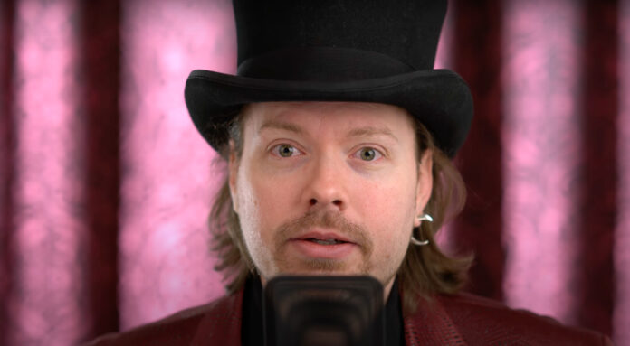 Richard Heart, founder of HEX, PulseChain and PulseX, wearing a top hat in a video still against a pink curtain