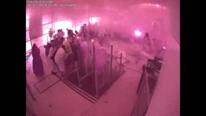 Surveillance camera frame showing smoke and fire at an airport gate as people react during an attack
