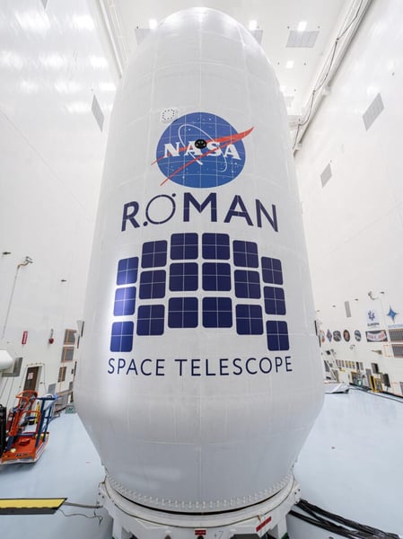 The Roman Space Telescope inside its payload fairing marked with the NASA and Roman logos