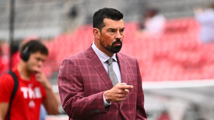 Ohio State coach Ryan Day in a plaid blazer points toward the field ahead of a game