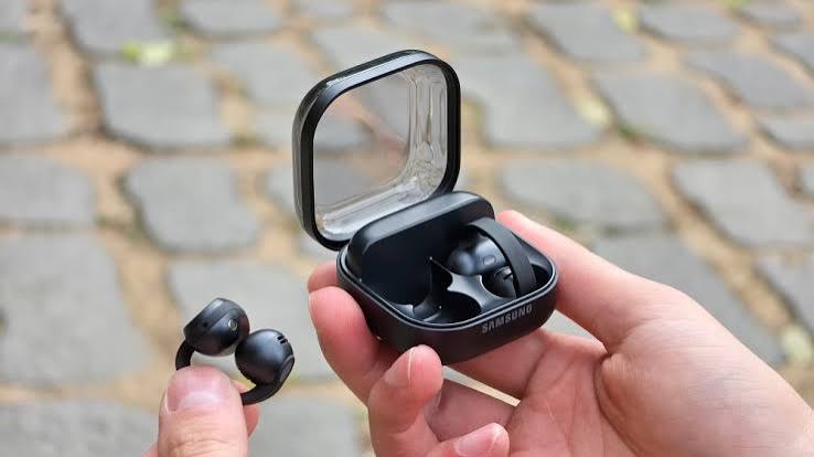 Hands holding Galaxy Buds On earbuds and an open black charging case