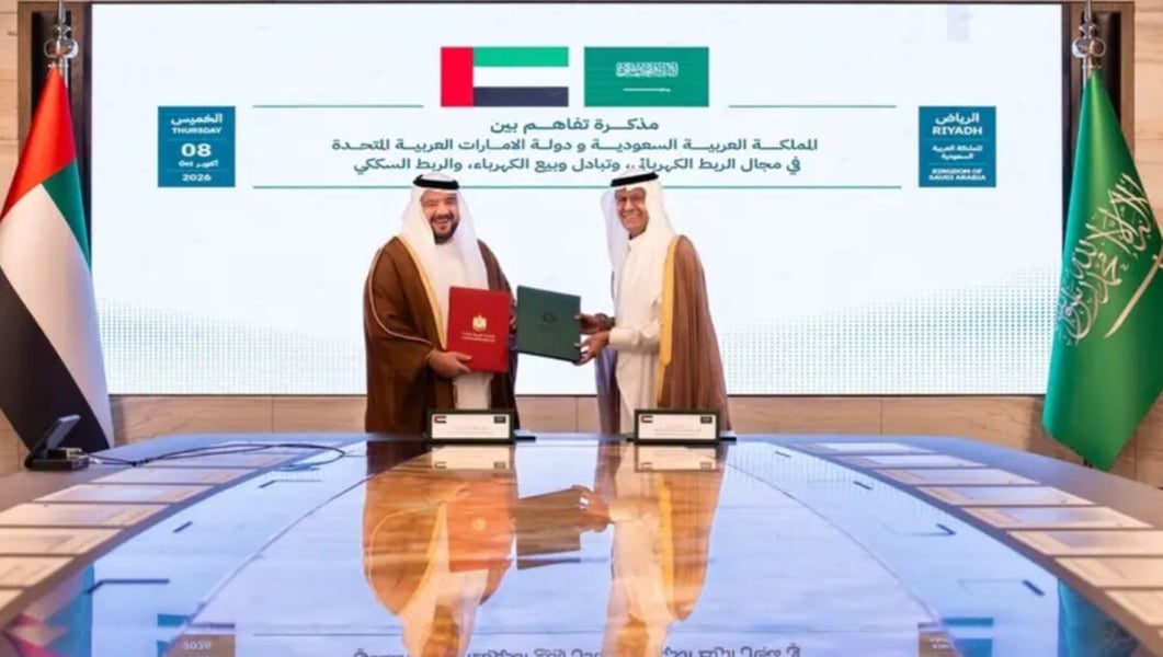Saudi and UAE ministers exchange signed memorandum folders in front of a screen showing both countries' flags and the date October 8, 2026