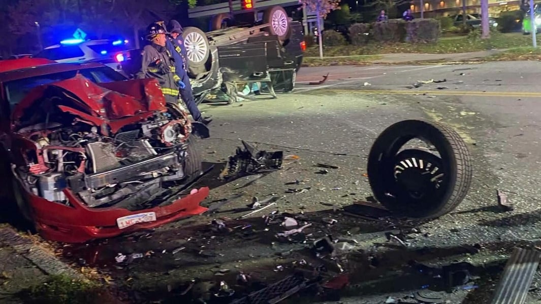 Overturned SUV, a wrecked red car and a detached wheel on a New Bedford street at night after the crash police say involved Shawn Oliver