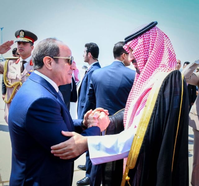 Egyptian President Abdel Fattah el-Sisi shakes hands with Saudi Crown Prince Mohammed bin Salman on a tarmac in Cairo as soldiers salute