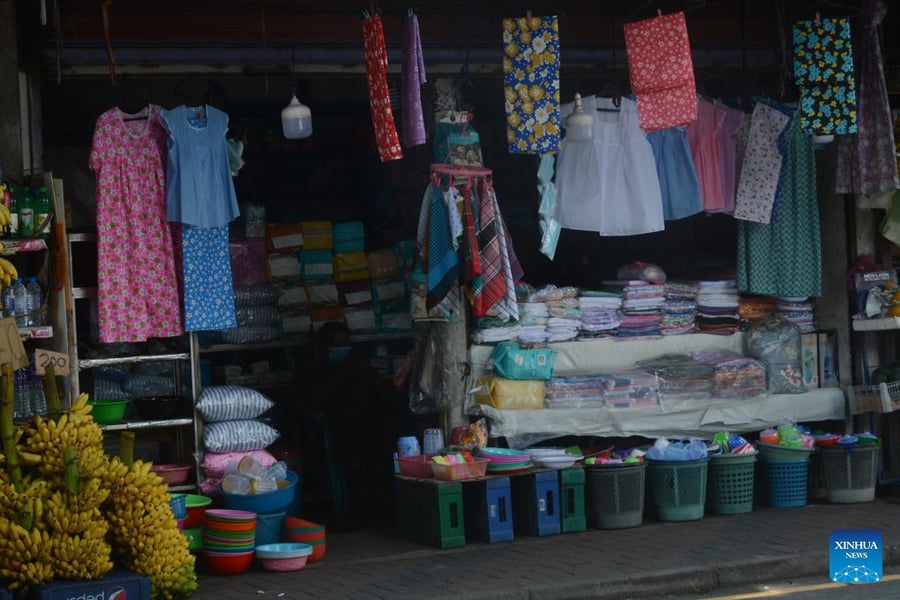 A roadside stall in Colombo displaying clothes, plastic ware and bananas, with its lights off