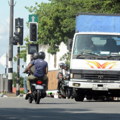 Motorcyclists and a truck pass a traffic light that is not working at a junction in Colombo, Sri Lanka