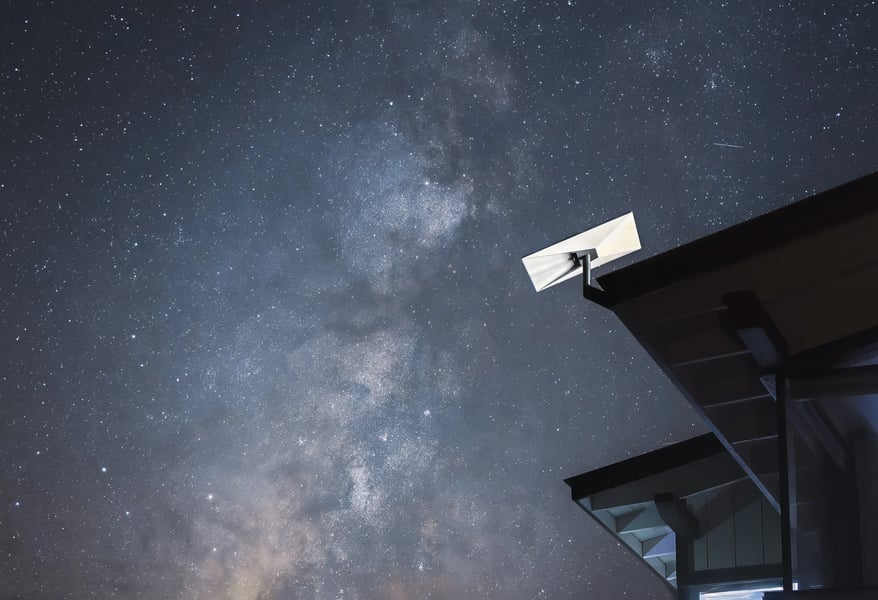 A Starlink satellite terminal mounted on a roof edge beneath the Milky Way