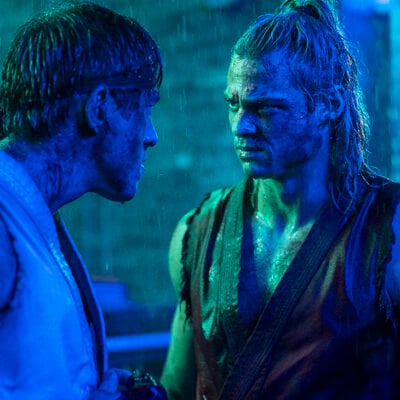 Andrew Koji and Noah Centineo face each other in a rain-soaked blue-lit scene from Paramount's Street Fighter