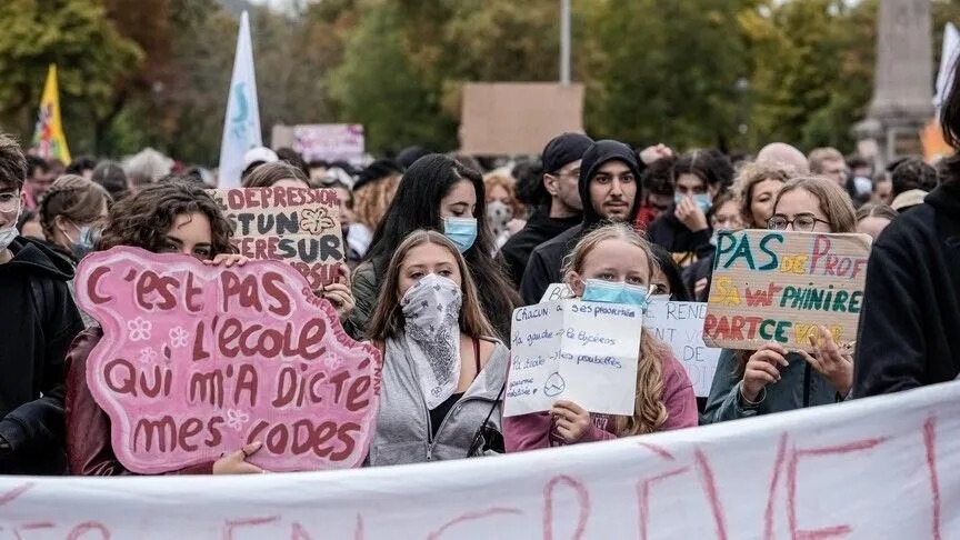 Students in face masks hold hand-written signs in French at a street protest, in a photograph Anadolu ran with its Brussels report