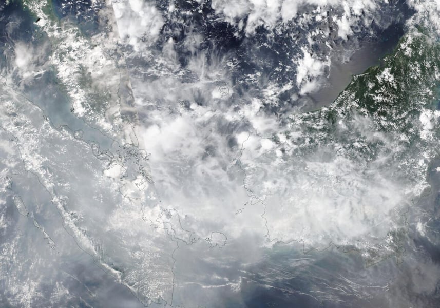 Satellite view of Sumatra, the Malay Peninsula and western Borneo on October 16, 2026 under a grey-white veil of cloud and haze, with coastlines outlined
